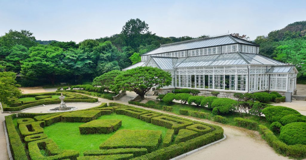 Victorian-style Grand Greenhouse at Changgyeonggung Palace, colonial-era glass structure preserved as historical monument alongside traditional Korean architecture
